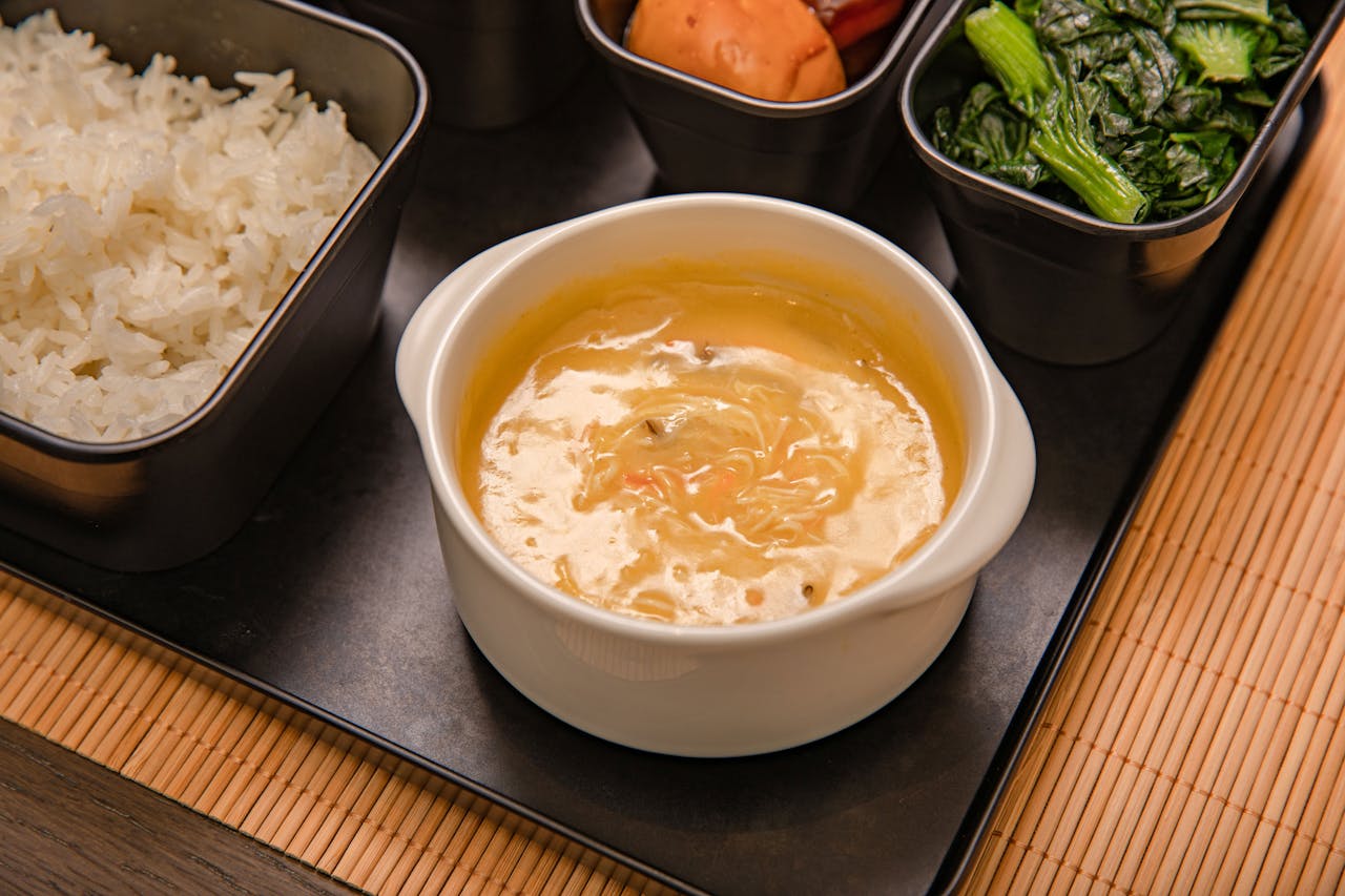 Home An appetizing Asian meal set with rice, soup, and vegetables, elegantly presented for a delightful dining experience.